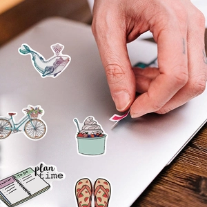 Waterproof cartoon graffiti stickers set applied to a laptop lid on a wooden desk