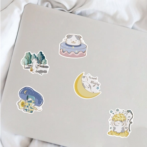 Close-up of five cute fat cat cartoon stickers applied to a grey laptop lid
