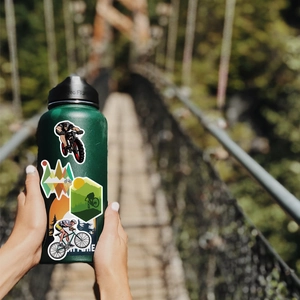 Pegatinas impermeables de ciclismo de montaña en una botella deportiva en el bosque