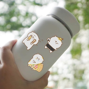 Hand holding a cream-colored insulated tumbler with cute cartoon bear sticker designs