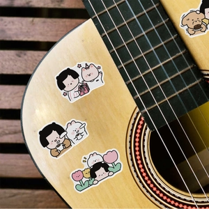 Waterproof cartoon bear and girl stickers applied on a wooden acoustic guitar surface