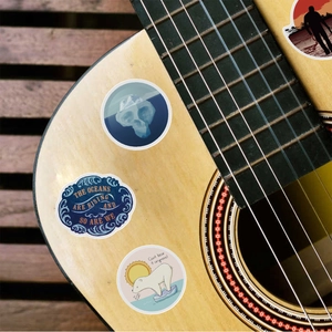 Macro view of waterproof climate change stickers with eco-themed slogans on a guitar surface