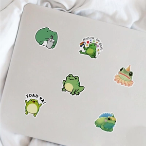Detailed view of waterproof cartoon frog stickers on laptop featuring cute green aesthetics
