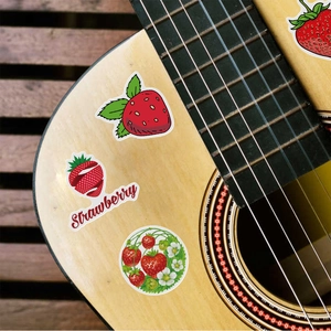 Detailed view of waterproof cartoon strawberry stickers applied on a guitar surface