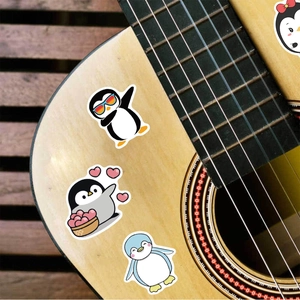 Vue détaillée d'autocollants pingouins étanches appliqués sur une guitare en bois clair