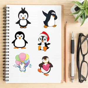 Autocollants de pingouins étanches posés sur un carnet avec accessoires de bureau