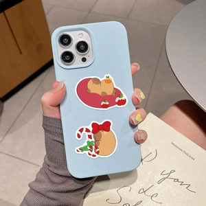 Close-up of light blue iPhone case with festive Christmas capybara cartoon illustrations