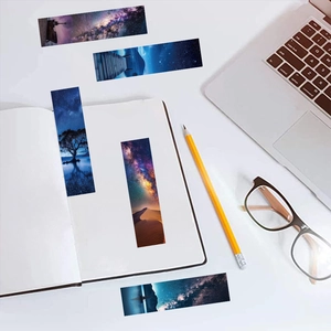 Detail view of artistic bookmarks featuring galaxy and night landscape scenes on a white desk
