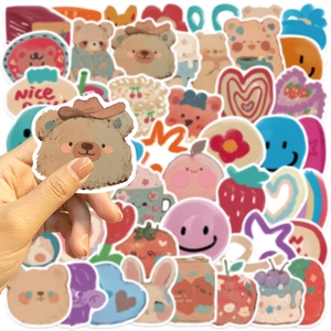 Close-up of cute cartoon bear oil painting sticker being held for DIY laptop decoration