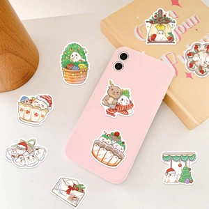 Cute cartoon ghost Christmas stickers applied on pink smartphone and white tabletop