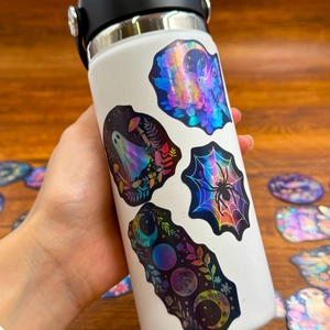 50pcs laser holographic stickers with Halloween and nature motifs on wooden table