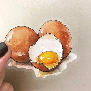 Hand holding watercolor egg stickers with transparent edges for DIY journal scrapbooking