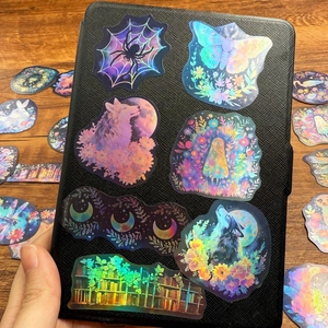 Holographic cartoon doodle stickers with laser effect on black laptop cover and wooden desk
