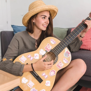 Pink bow religious stickers with faith quotes applied to a guitar in a lifestyle scene