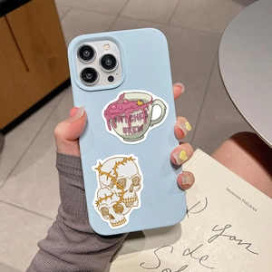 Detail of light blue phone case with witch themed stickers being held by hand