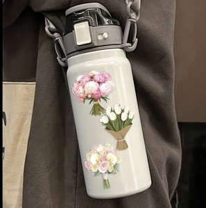 Close-up of floral PET stickers applied on a grey water bottle with nylon strap