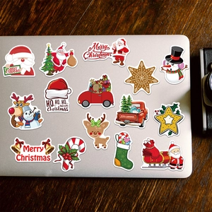Assorted Christmas stickers on laptop featuring Santa and reindeer on wooden background