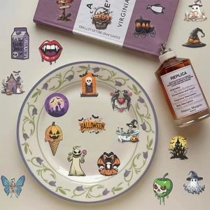 Flat lay of gothic Halloween PET stickers with pumpkin and ghost motifs on a floral plate