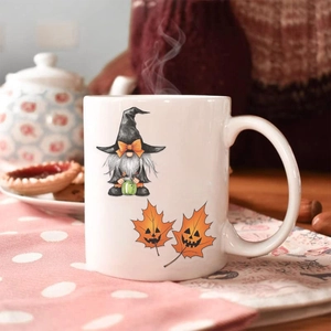 Cozy autumn scene with a Halloween gnome ceramic mug and maple leaf decorations