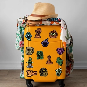 Neon Halloween stickers set on yellow suitcase featuring ghosts pumpkins and bats