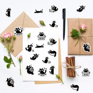 Flat lay of cute black and white cartoon cat stickers with stationery and dried flowers