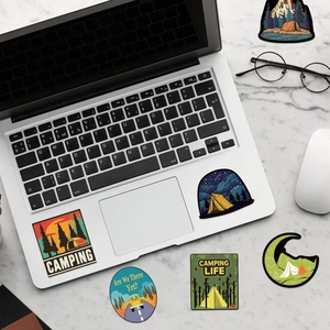 Flat lay of waterproof outdoor camping stickers on a marble desk with lifestyle props