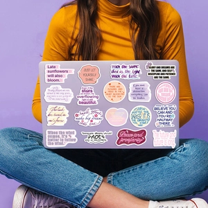 A close-up of a laptop decorated with colorful dream-like inspirational quote stickers