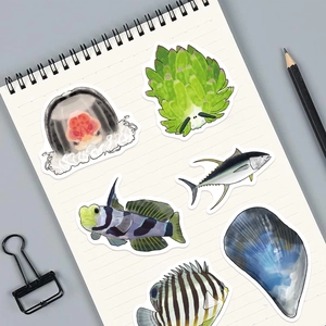 Détail d'autocollants colorés de créatures marines sur un carnet avec des fournitures