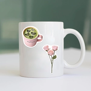 Close-up of pink coffee cup and floral stickers on a white ceramic mug for DIY decoration