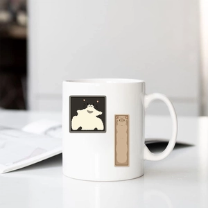 Close-up of a white ceramic mug featuring cute cartoon cat illustrations on a clean desk