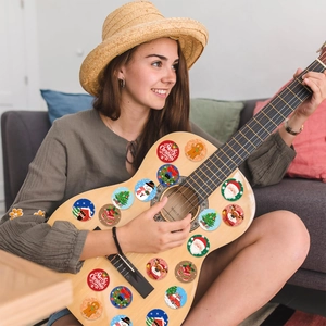 Detailed view of round Christmas stickers with Santa and reindeer on a guitar