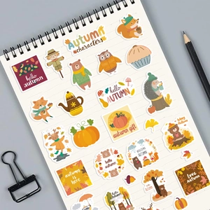 Detailed view of autumn-themed DIY stickers with fox and bear motifs on a spiral notebook