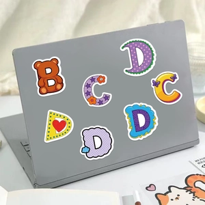 Cartoon alphabet stickers featuring bear and floral patterns on a laptop lid