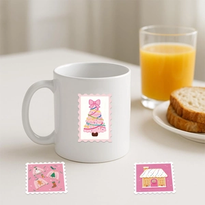 Close-up of a white ceramic Christmas mug with pink stamp-style tree and holiday stickers