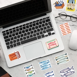Detailed view of colorful sardine theme stickers applied on a silver laptop and marble surface