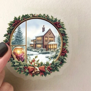 Vue macro d'autocollant de Noël rond montrant une maison enneigée et une couronne de houx