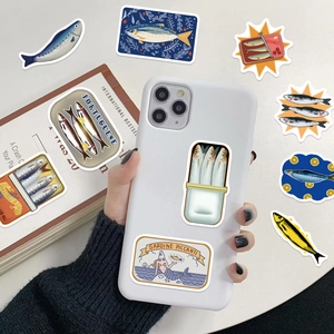 Close-up of vintage sardine tin stickers on a white phone case with retro book background