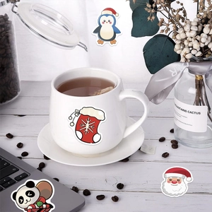 Gros plan d'autocollants de Noël mignons avec Père Noël et pingouin sur un mug blanc