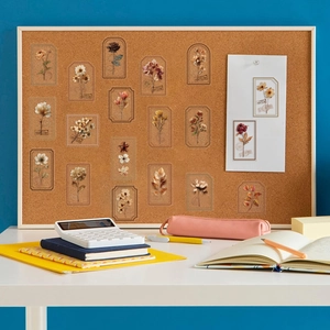 Détail d'autocollants floraux vintage sur panneau en liège avec accessoires de bureau