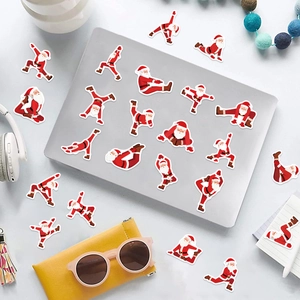 50pcs Yoga Santa Claus vinyl stickers decorating a laptop on a white creative desk