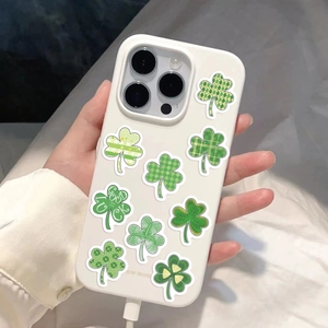 Close-up of iPhone case featuring green lucky clover stickers and Good Luck text