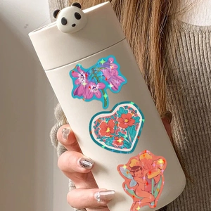 Close-up of fairy and flower stickers with sparkling film applied on a white thermos bottle