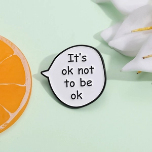 Minimalist enamel speech bubble pin with 'It's ok not to be ok' quote on green background