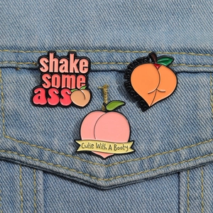 Detailed close-up of cute peach enamel pins and badges on a light blue denim jacket
