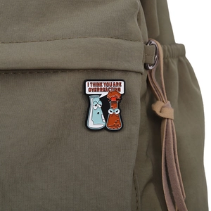 Detail of funny chemistry enamel pin with science beaker on green canvas backpack texture