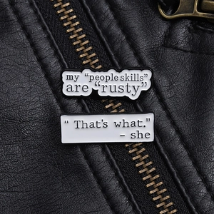 Detail of funny quote enamel pins displayed on a black leather jacket texture background