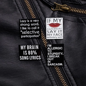 Close-up of witty English phrase enamel pins on a black leather jacket collar