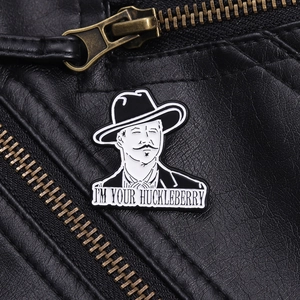 Detail of enameled I'M YOUR HUCKLEBERRY pin badge on black leather jacket texture