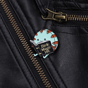Detail of cartoon enamel pin with dark magic book pinned on a black leather jacket