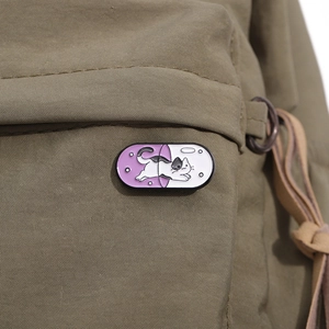 Detailed macro shot of capsule cat enamel pin on military green canvas bag fabric